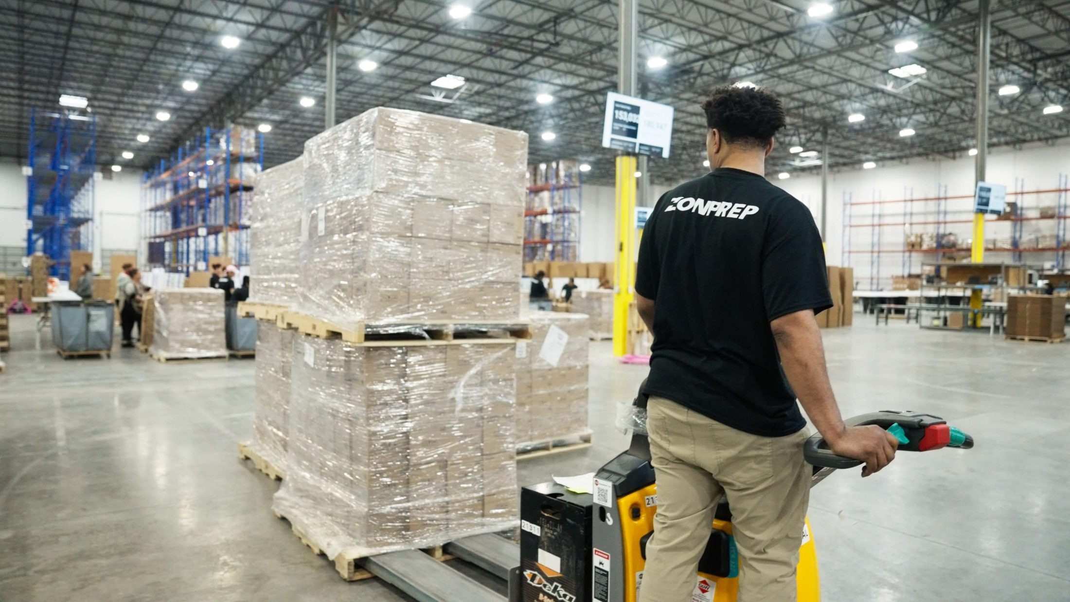 ZonPrep team member moving a stretch-wrapped pallet with an electric pallet jack