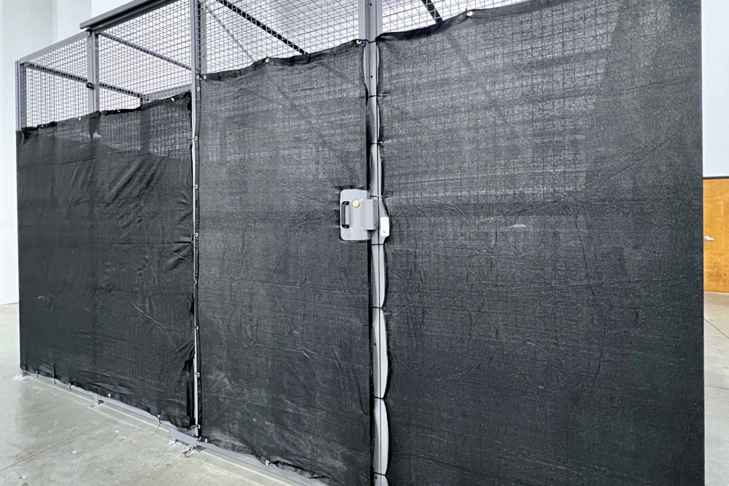 Cage wrapped in black privacy mesh inside a ZonPrep warehouse