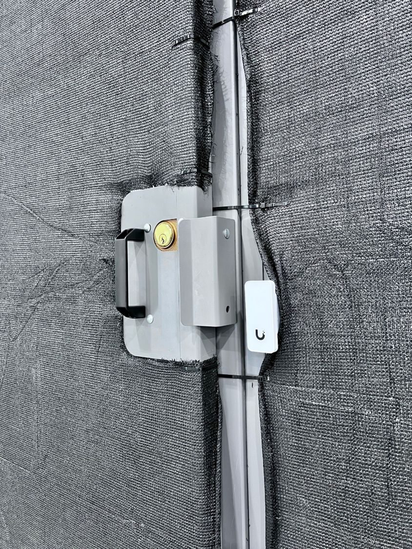 Keyed lock and door sensor on a storage cage covered in privacy mesh